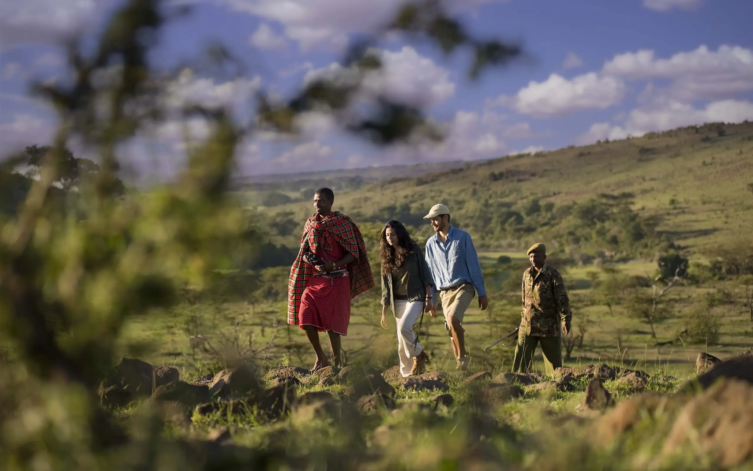 Guides and guests walking through savanna landscape, Kenya
