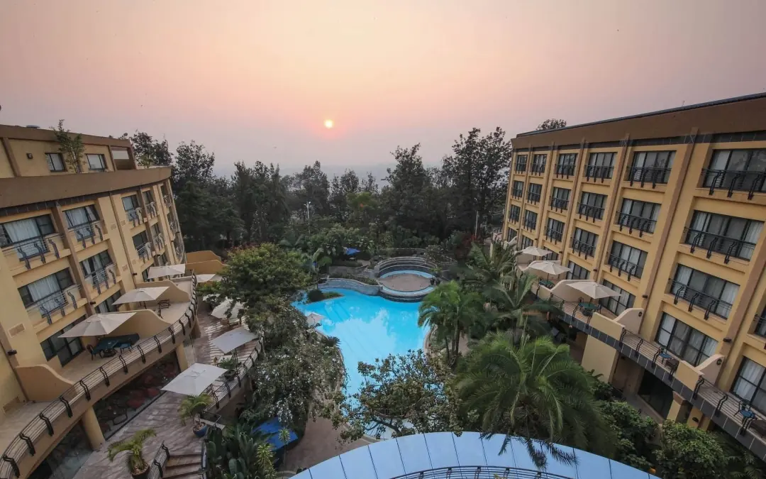 Resort pool area at dusk with surrounding buildings and trees, Kigali Serena Hotel, Kigali, Rwanda