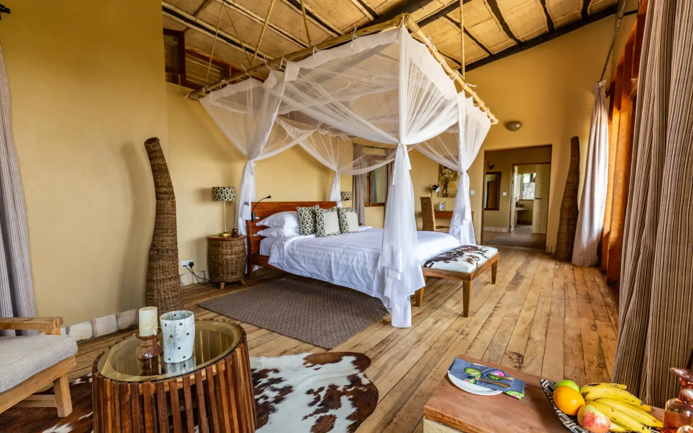 Spacious bedroom with four-poster canopy bed and wooden furnishings, Kyambura Gorge Lodge, Queen Elizabeth NP, Uganda