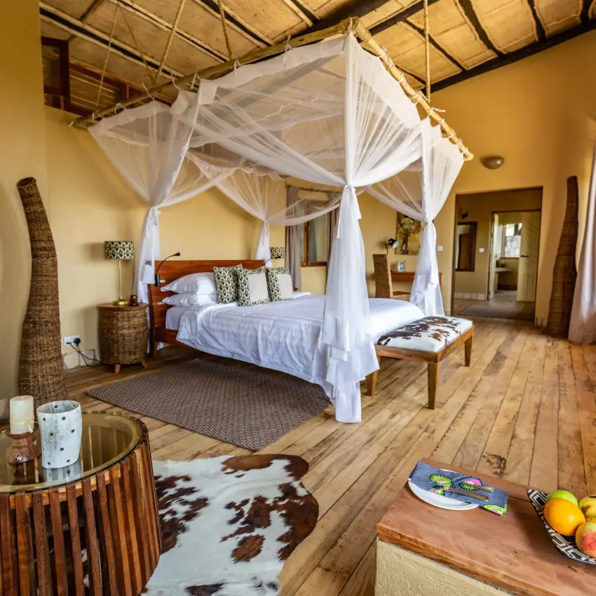 Spacious bedroom with four-poster canopy bed and wooden furnishings, Kyambura Gorge Lodge, Queen Elizabeth NP, Uganda