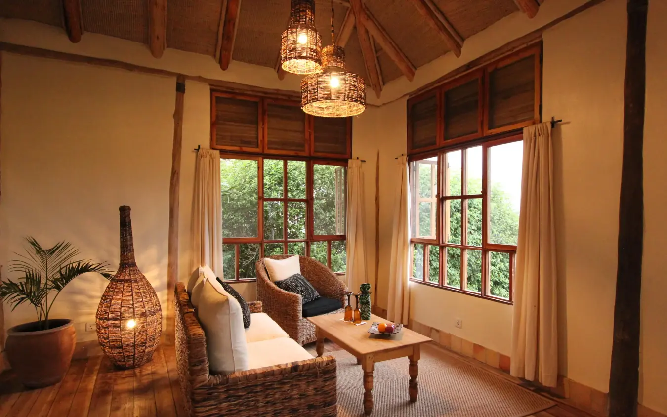 Interior lounge with woven furniture and large windows overlooking greenery, Kyambura Gorge Lodge, Queen Elizabeth NP, Uganda