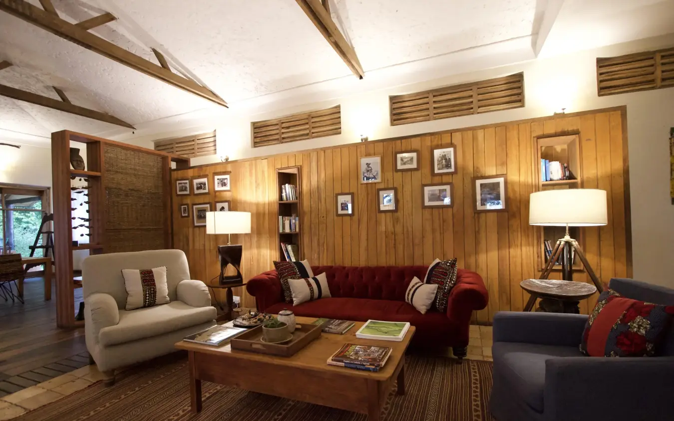 Wood-paneled lounge with fireplace seating and artwork, Kyambura Gorge Lodge, Queen Elizabeth NP, Uganda