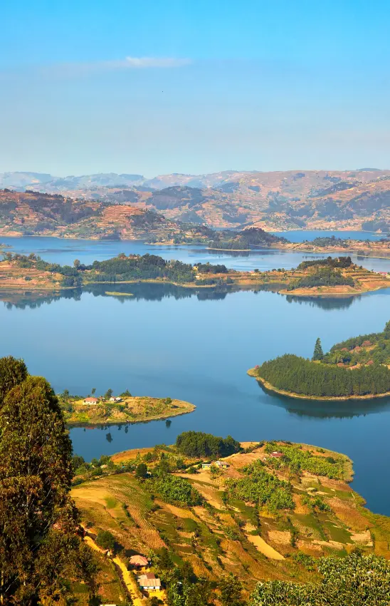 Aerial view of forested islands dotting blue lake with mountains