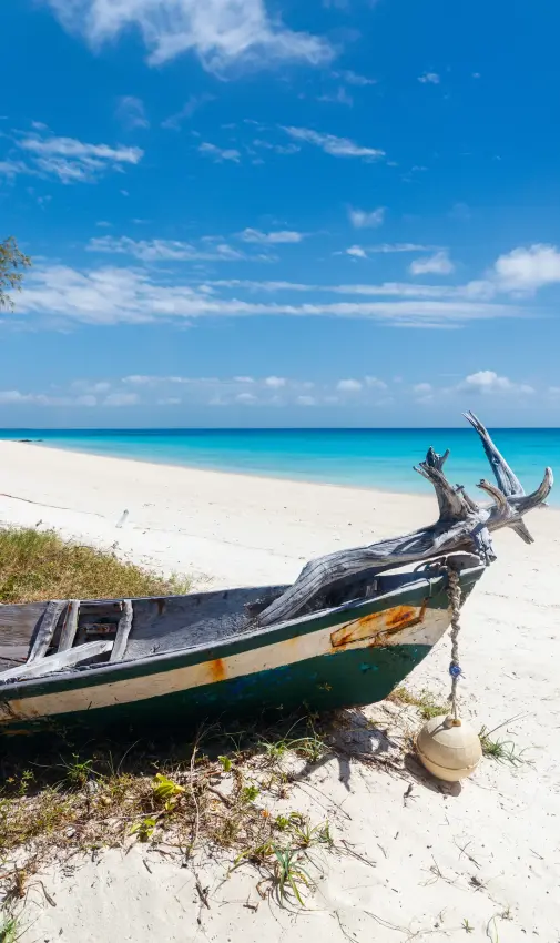 Wooden fishing boat beached on white sand tropical shore