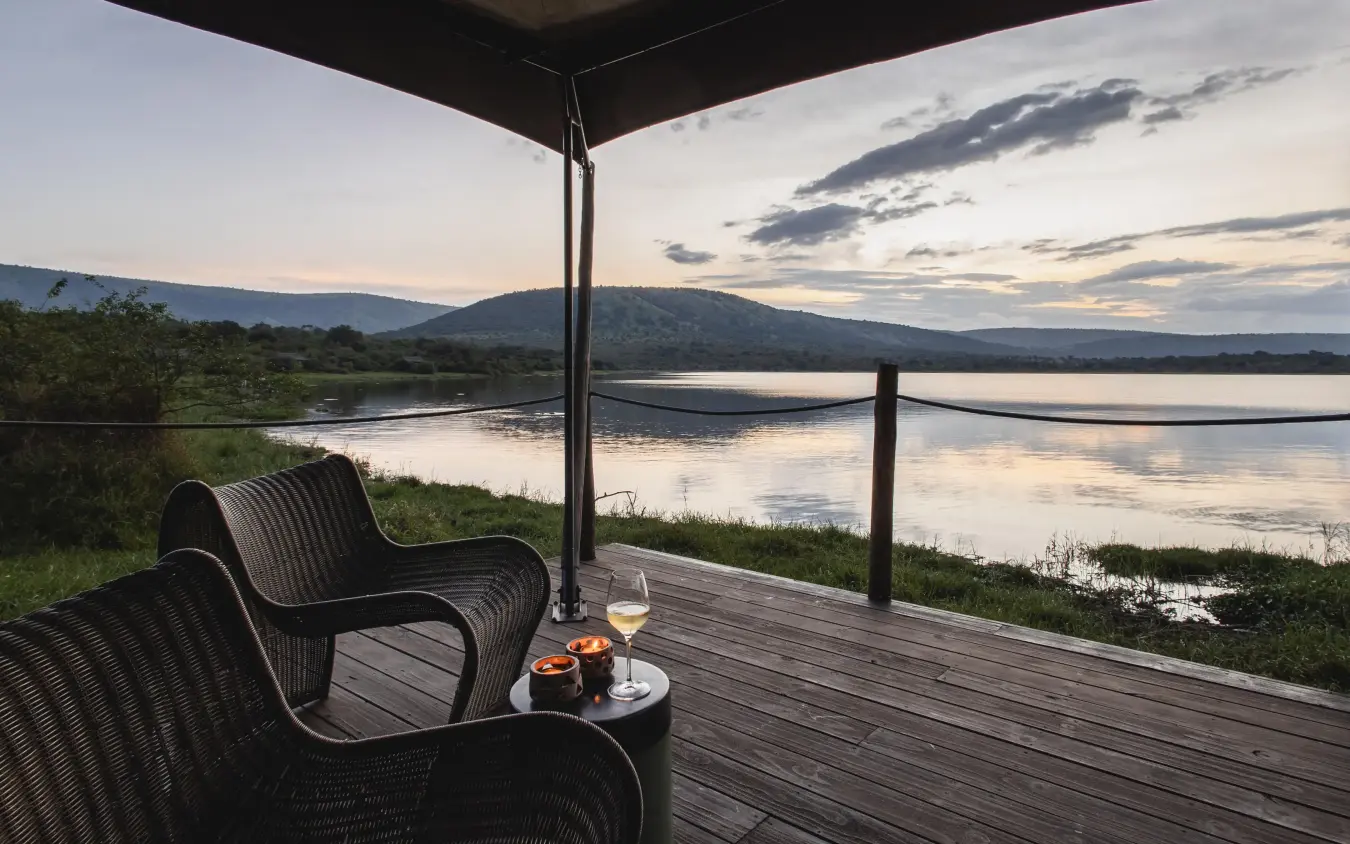 Wooden deck with chairs overlooking river at dusk, Magashi Camp, Akagera National Park, Rwanda