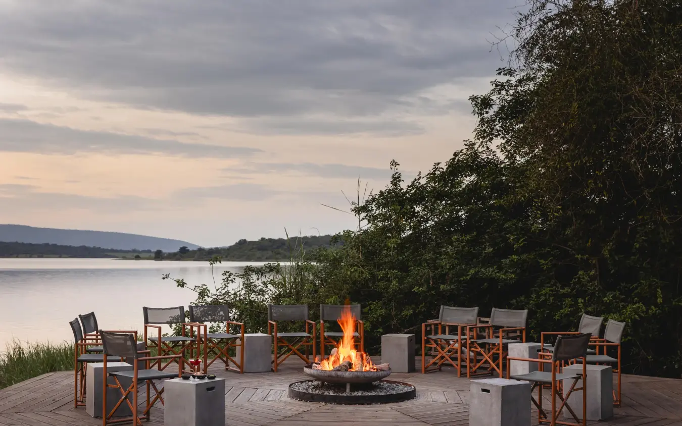 Waterfront deck with fire pit and lounge seating at dusk, Magashi Camp, Akagera National Park, Rwanda