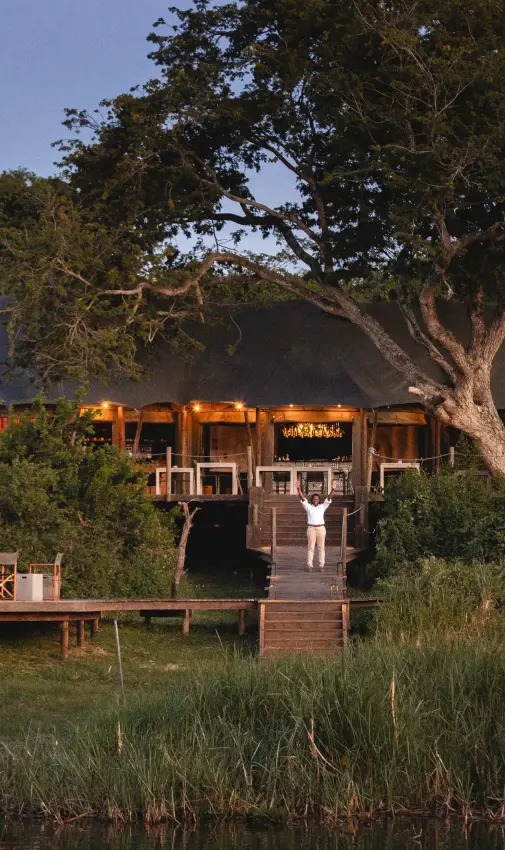 Waterfront lodge with canvas tents lit at dusk, Magashi Camp, Akagera National Park, Rwanda