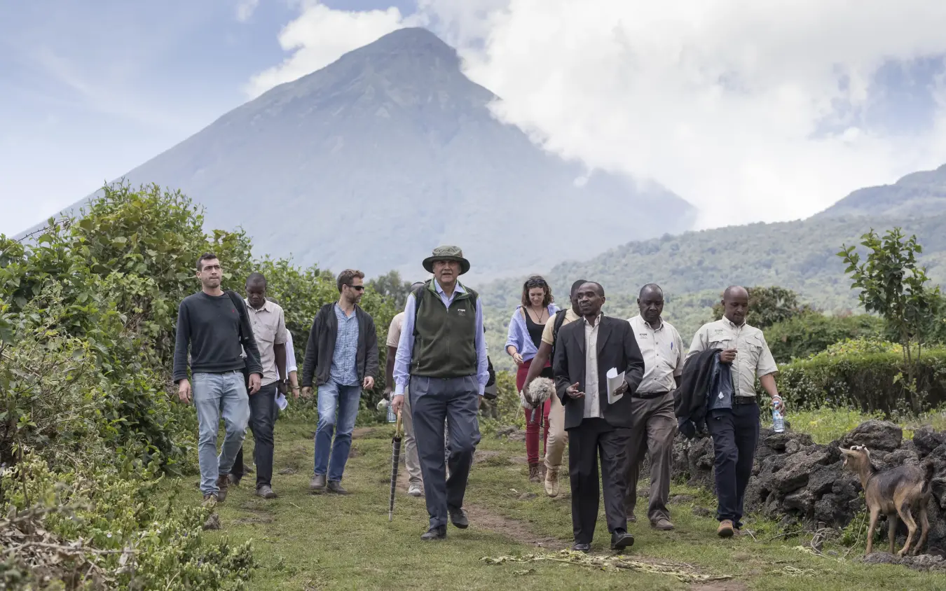 Group hiking through volcanic landscape with mountain peak backdrop, Mount Gahinga Lodge, Mgahinga National Park, Uganda