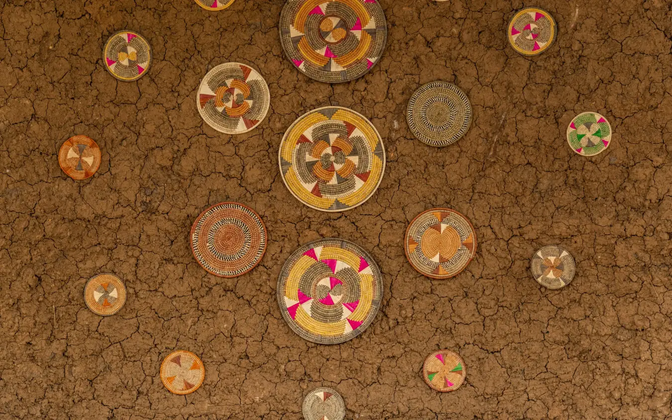 Colorful woven circular baskets arranged on earth ground, Mount Gahinga Lodge, Mgahinga National Park, Uganda