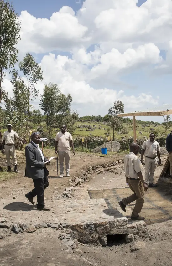 Community gathering at rural settlement with thatched structures, Mgahinga National Park, Uganda