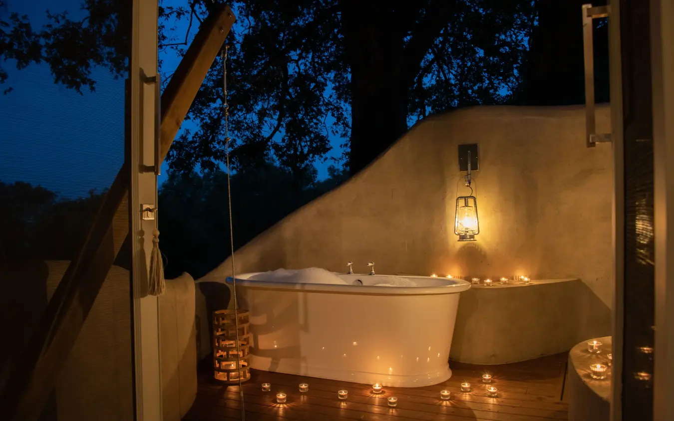 Outdoor bathtub on wooden deck at dusk with candlelight, Mpala Jena, Victoria Falls, Zimbabwe