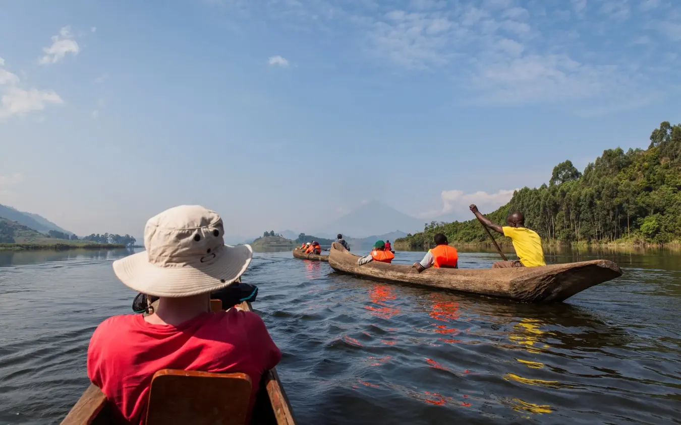 Guests paddling traditional wooden boats on calm lake, Mutanda Lake Resort, Lake Mutanda, Uganda
