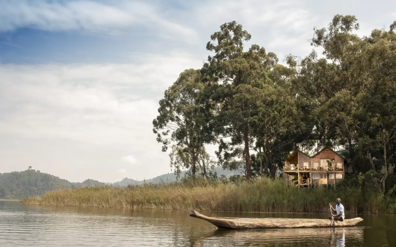 Person in wooden boat on calm lake with reeds, Mutanda Lake Resort, Lake Mutanda, Uganda