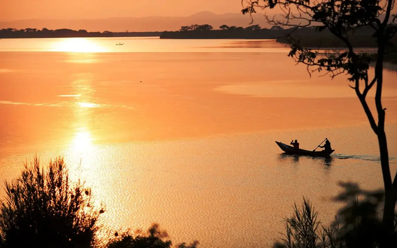 Fishing boats on calm lake at golden sunrise, Mutanda Lake Resort, Lake Mutanda, Uganda