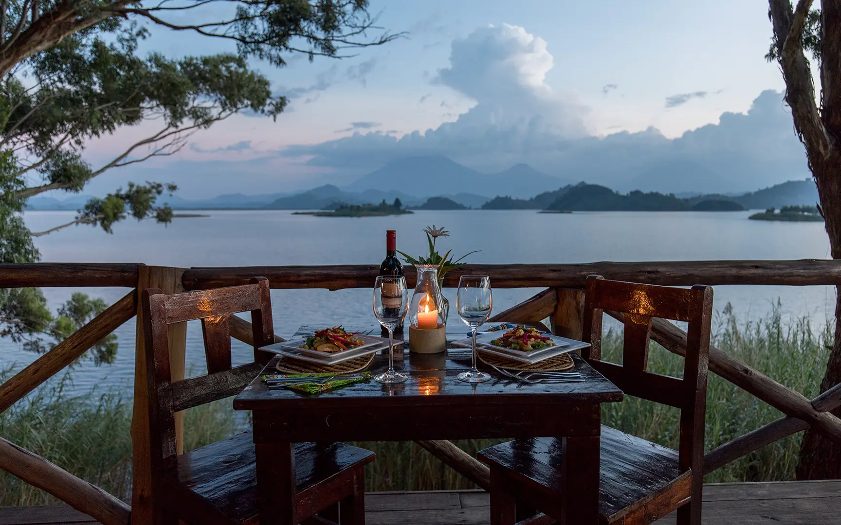 Lakeside dining setup on wooden deck at sunset, Mutanda Lake Resort, Lake Mutanda, Uganda