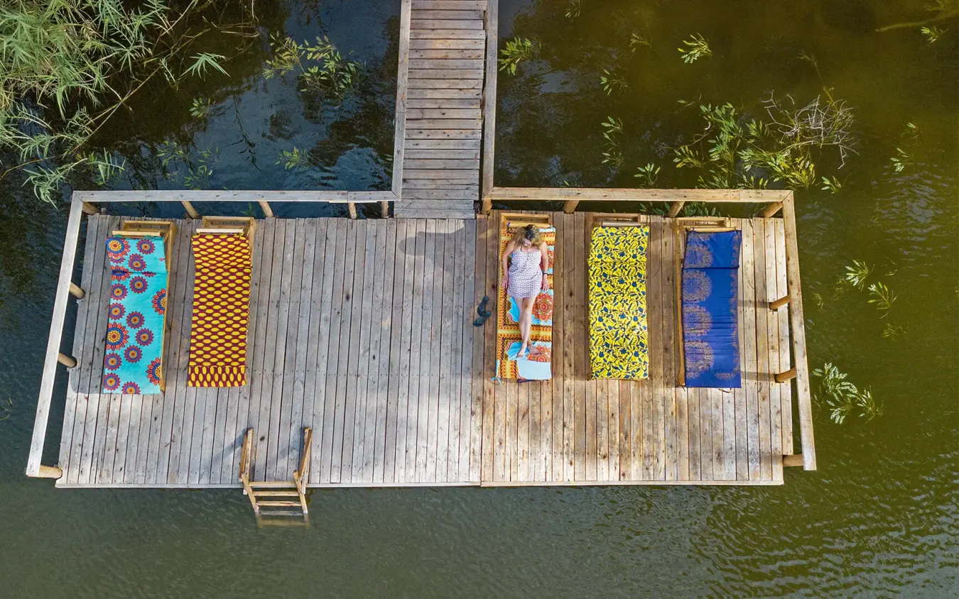 Aerial view of wooden deck platform over water with lounging guests, Mutanda Lake Resort, Lake Mutanda, Uganda