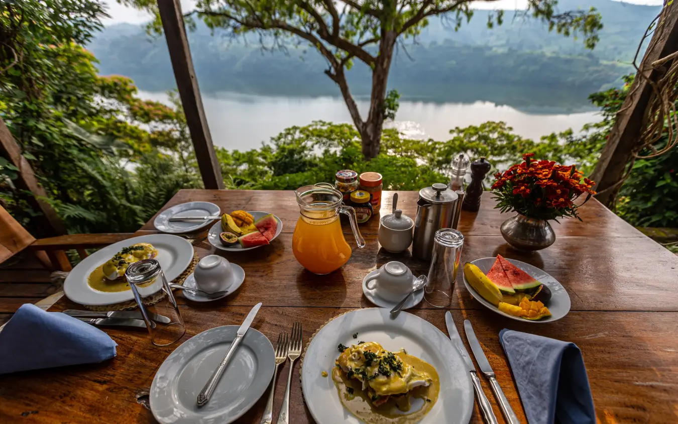 Breakfast table overlooking lake with mountains beyond, Ndali Lodge, Kibale Forest, Uganda