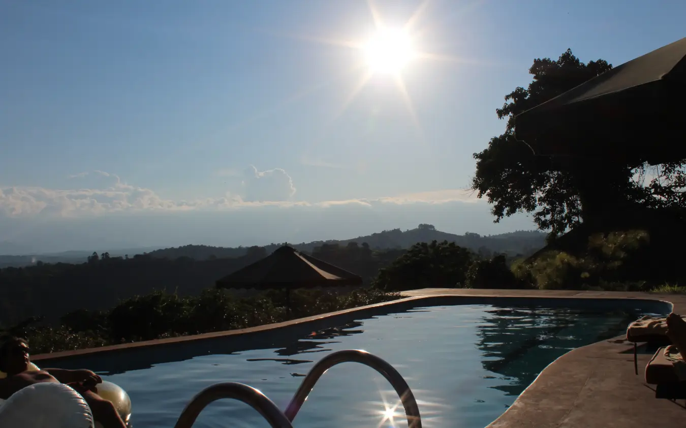 Infinity pool overlooking forested valley under bright sun, Ndali Lodge, Kibale Forest, Uganda