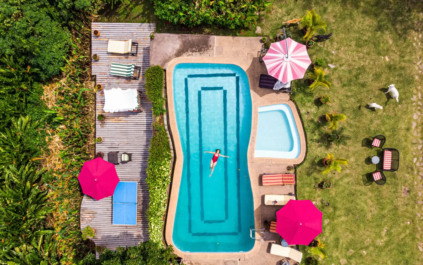Overhead view of resort pool with lounging guests and umbrellas, Ndali Lodge, Kibale Forest, Uganda