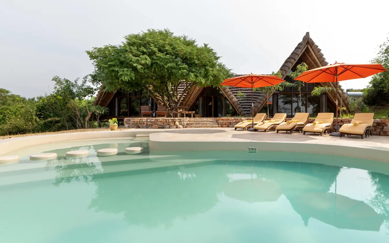 Resort pool with lounge chairs and thatched roof structure, Nile Safari Lodge, Murchison Falls NP, Uganda