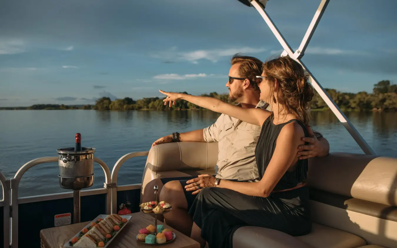 Couple relaxing on boat with refreshments and river view, Old Drift Lodge, Victoria Falls, Zimbabwe
