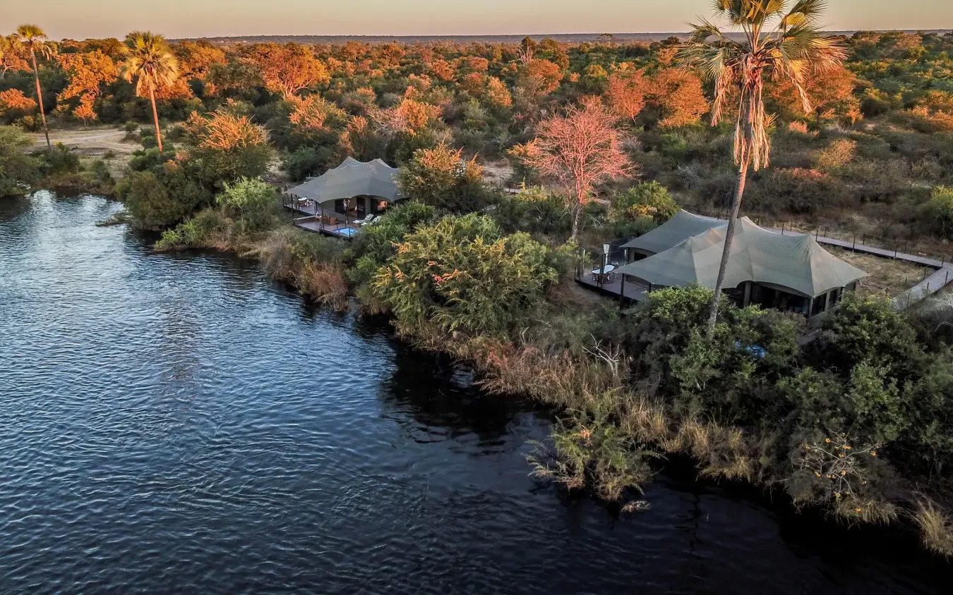 Riverside lodge tents surrounded by woodland at sunset, Old Drift Lodge, Victoria Falls, Zimbabwe