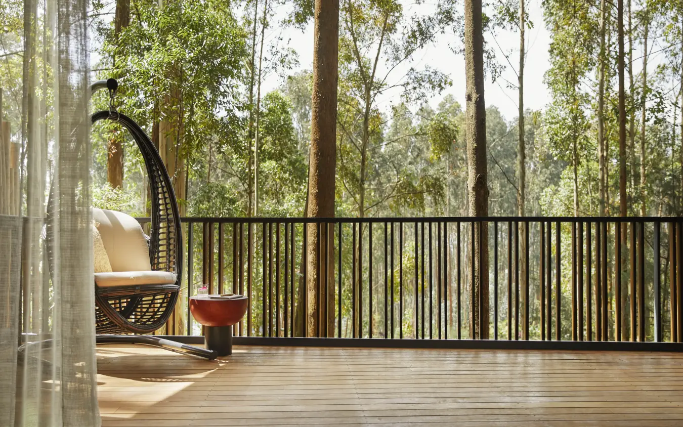 Wooden deck with chair overlooking forested valley, Gorilla’s Nest, Volcanoes National Park, Rwanda