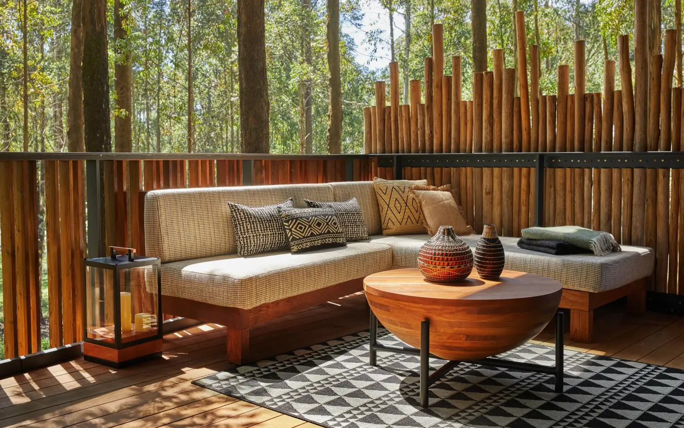 Wooden deck lounge with sofa, coffee table, forest backdrop, Gorilla’s Nest, Volcanoes National Park, Rwanda