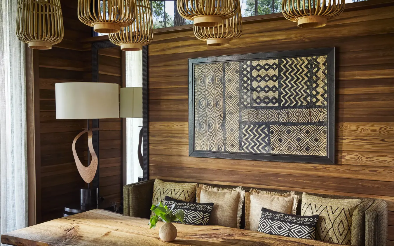 Wooden lounge area with patterned artwork and woven pendant lights, Gorilla’s Nest, Volcanoes National Park, Rwanda