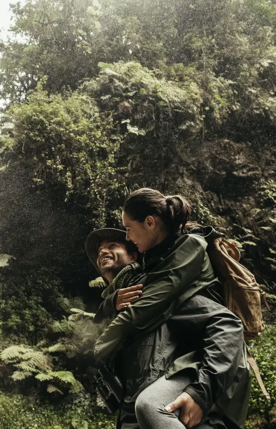 Adult carrying child near waterfall in lush forest, Nyungwe House, Nyungwe Forest, Rwanda