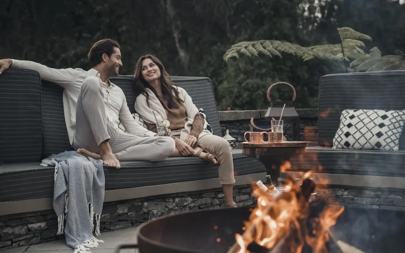 Couple relaxing on outdoor lounge seating by firepit, Nyungwe House, Nyungwe Forest, Rwanda