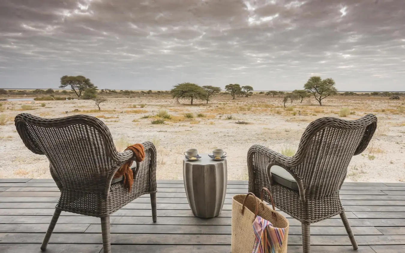 Two wicker chairs facing vast savanna landscape at sunset, Onguma The Fort, Etosha National Park, Namibia