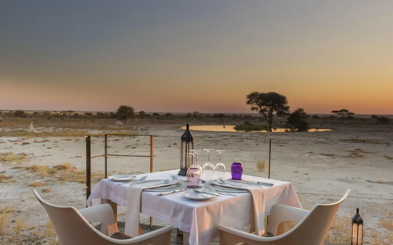 Dinner table setup overlooking waterhole at sunset, Onguma The Fort, Etosha National Park, Namibia