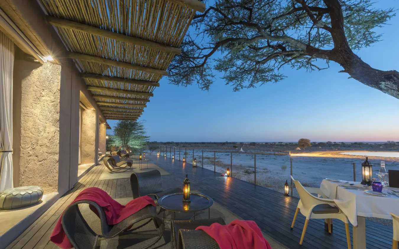Waterfront deck at dusk with lounge seating overlooking river, Onguma The Fort, Etosha National Park, Namibia