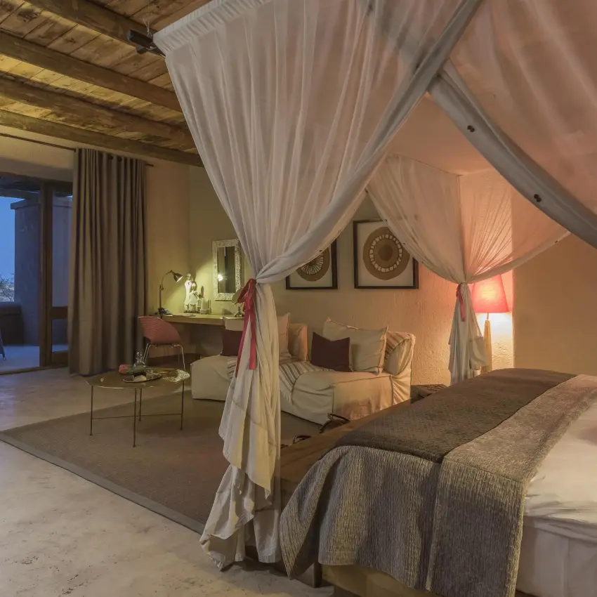 Luxury bedroom with canopy bed and evening mountain view, Onguma The Fort, Etosha National Park, Namibia