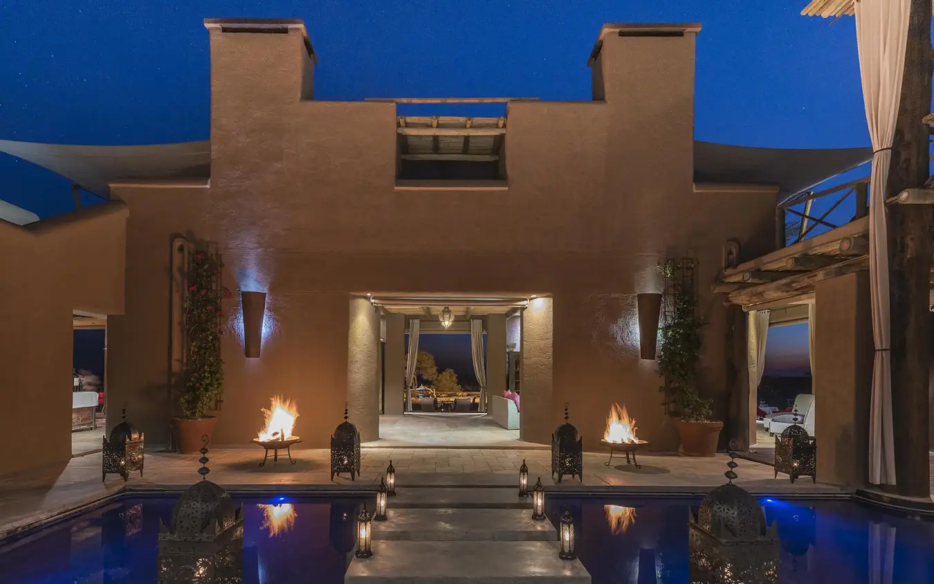 Illuminated courtyard with pools and fire features at dusk, Onguma The Fort, Etosha National Park, Namibia