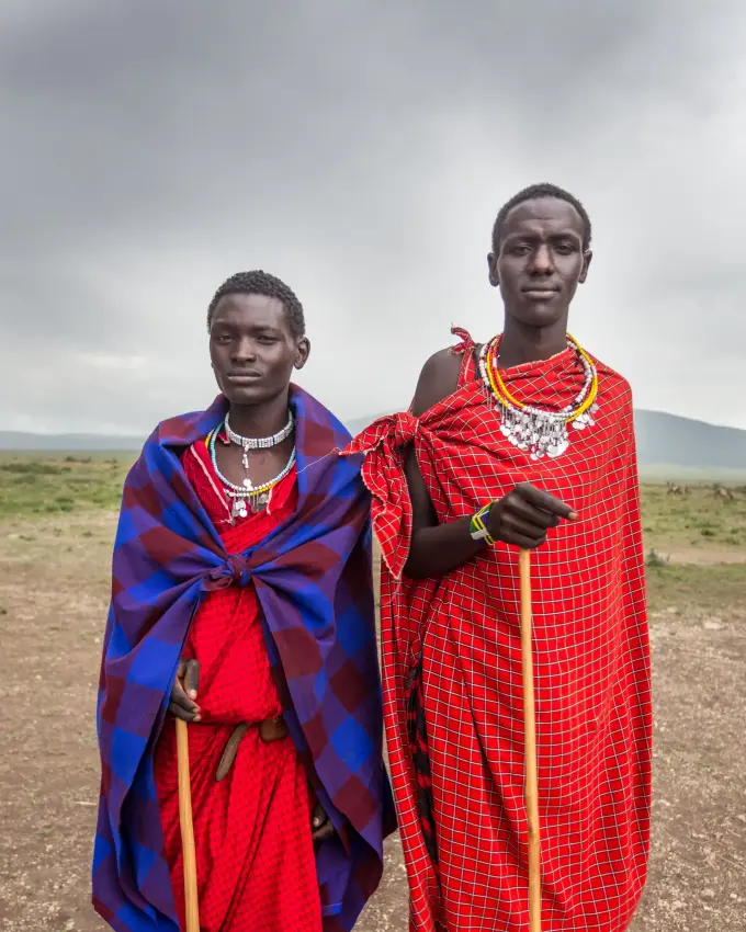 Two Maasai men in traditional red beaded clothing standing outdoors