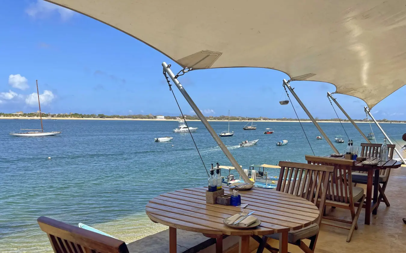Beachfront dining deck overlooking anchored sailboats and bay, Peponi Hotel, Lamu Archipelago, Kenya