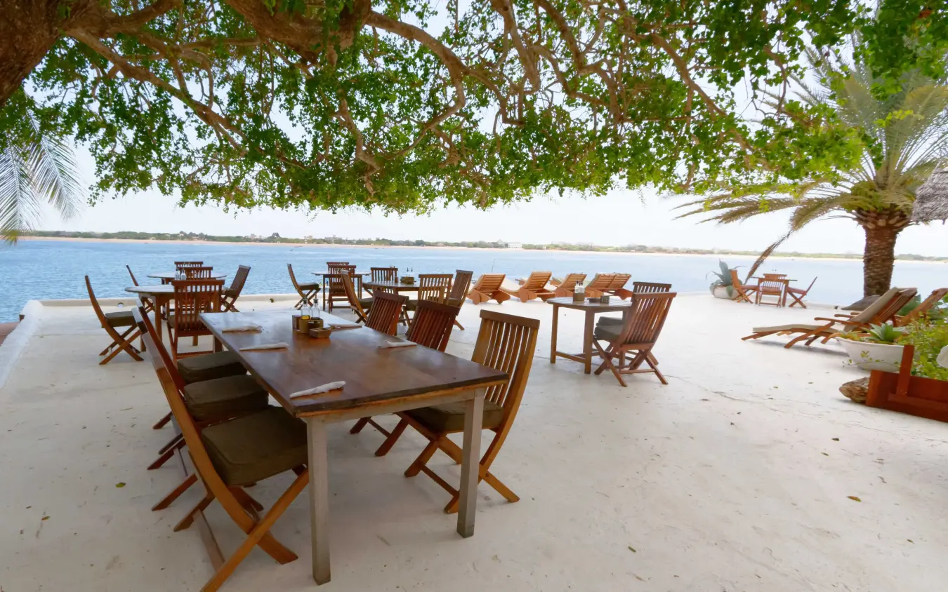 Beachfront dining setup with wooden tables and chairs, Peponi Hotel, Lamu Archipelago, Kenya