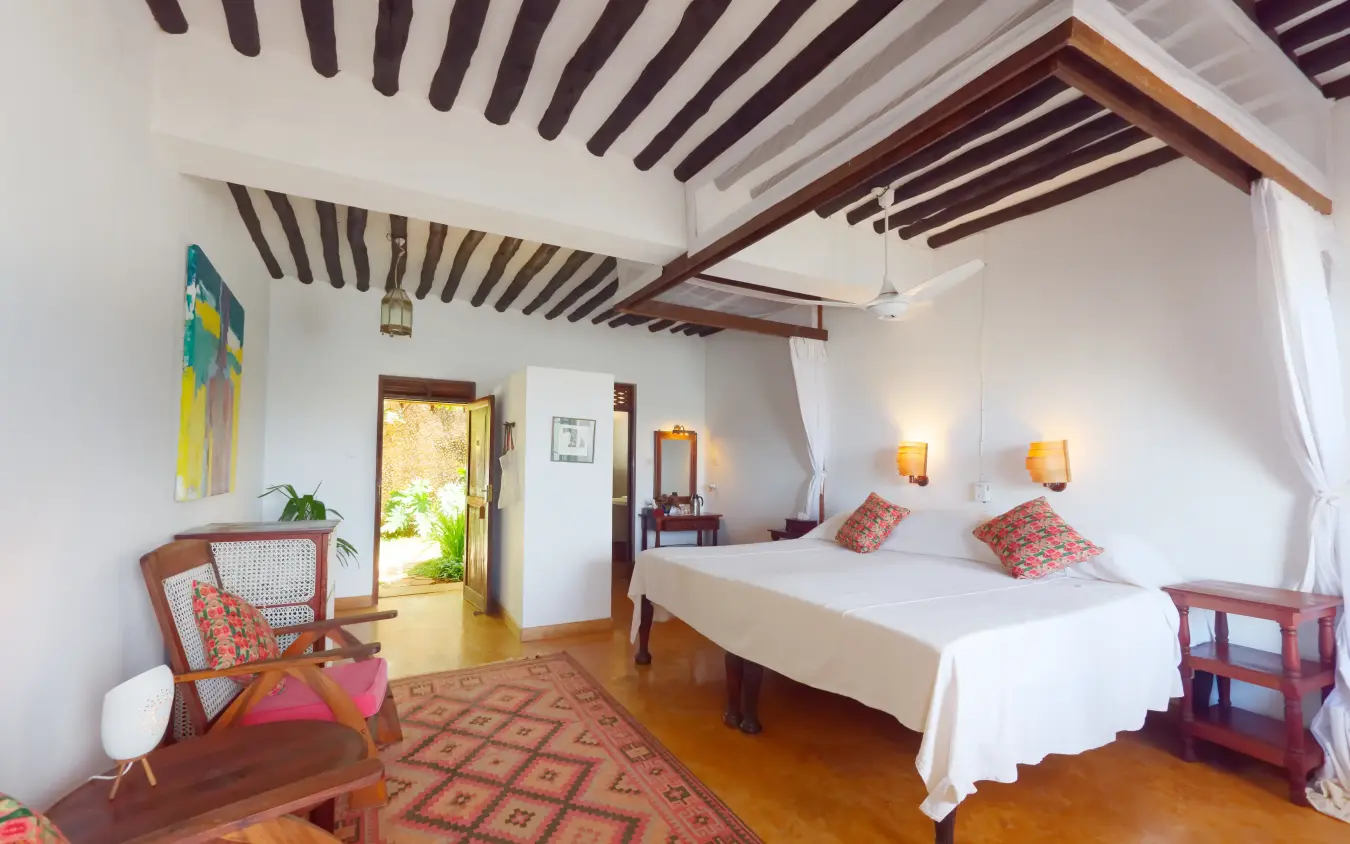 Spacious bedroom with wooden beamed ceiling and coastal decor, Peponi Hotel, Lamu Archipelago, Kenya