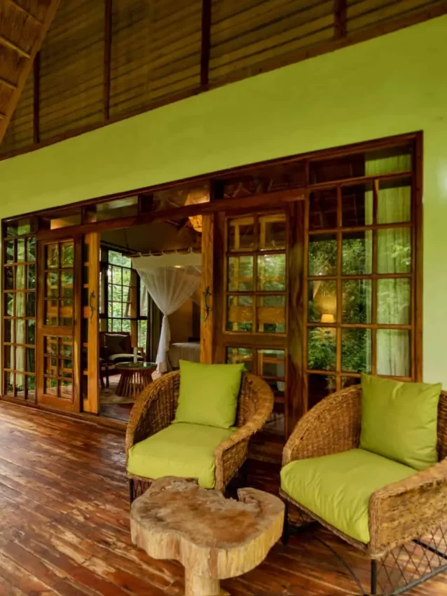 Covered wooden deck with wicker seating overlooking lush forest, Primate Lodge, Kibale Forest, Uganda