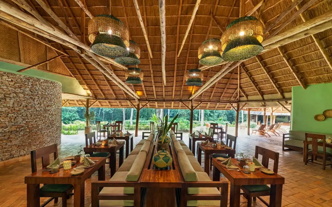 Open-air dining pavilion with wooden tables and hanging lights, Primate Lodge, Kibale Forest, Uganda