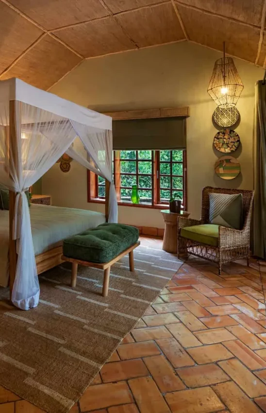 Canopy bed bedroom with terracotta floor and forest views, Primate Lodge, Kibale Forest, Uganda