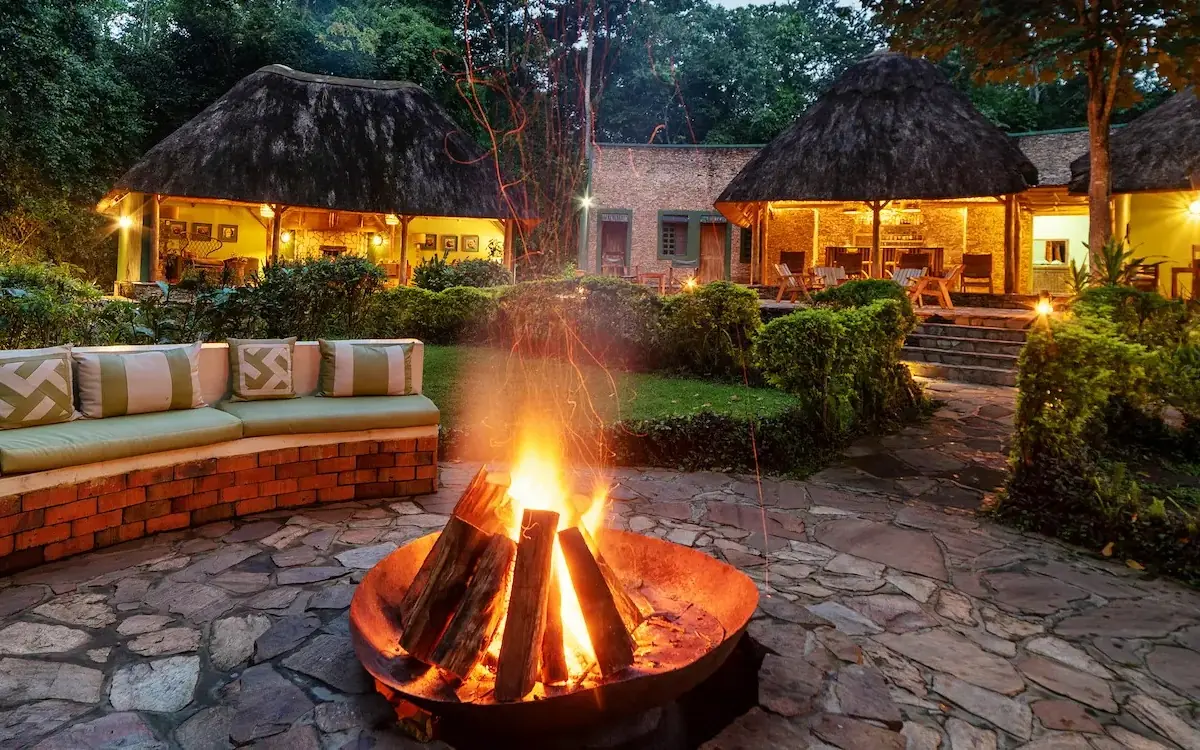 Evening firepit seating area with thatched roof bungalows, Primate Lodge, Kibale Forest, Uganda