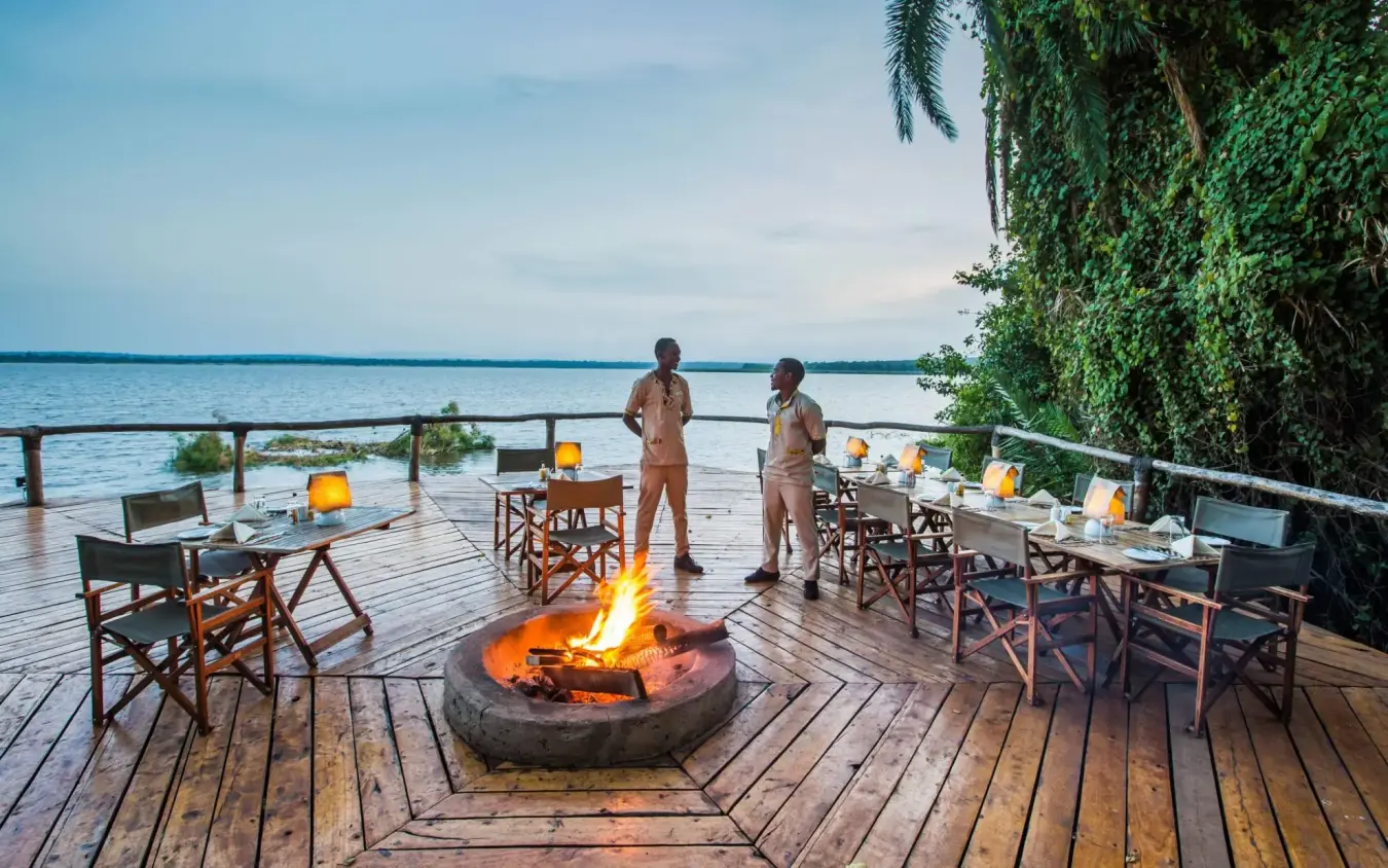 Waterfront deck at dusk with fire pit and seating, Ruzizi Tented Lodge, Akagera National Park, Rwanda