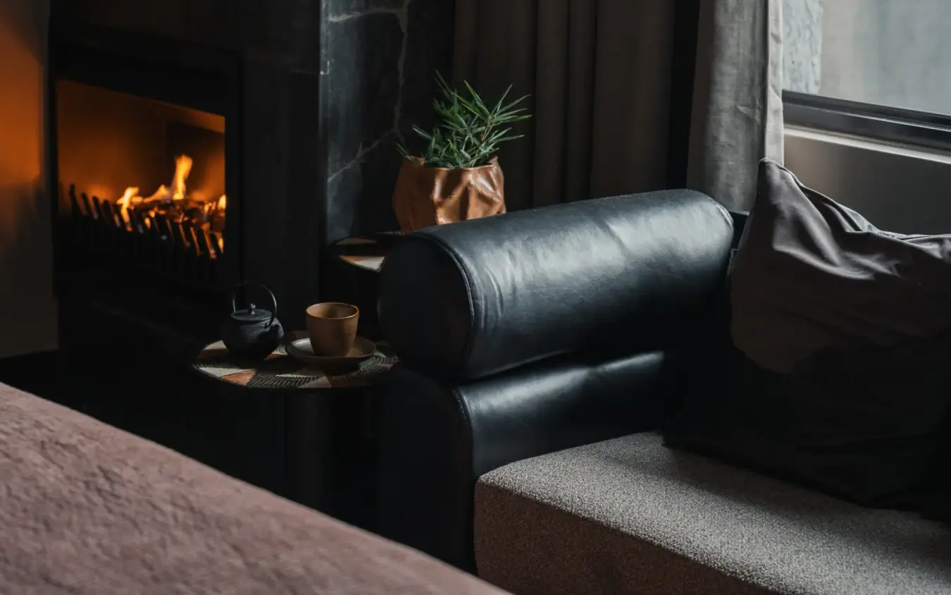 Black leather armchair by fireplace with warm lighting, Silverback Lodge, Bwindi Impenetrable Forest, Uganda