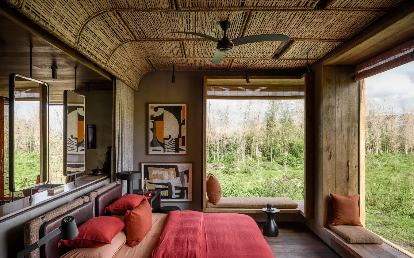 Bedroom with red bedding overlooking green forest landscape, Singita Kwitonda Lodge, Volcanoes National Park, Rwanda