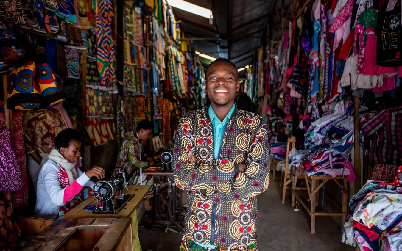 Man in patterned clothing at colorful fabric market stall, Singita Kwitonda Lodge, Volcanoes National Park, Rwanda