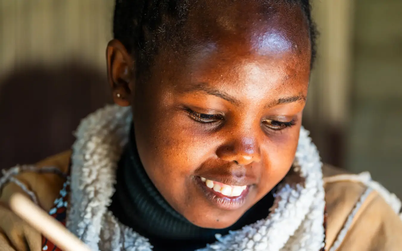 Woman smiling while holding wooden crafted object, Singita Kwitonda Lodge, Volcanoes National Park, Rwanda