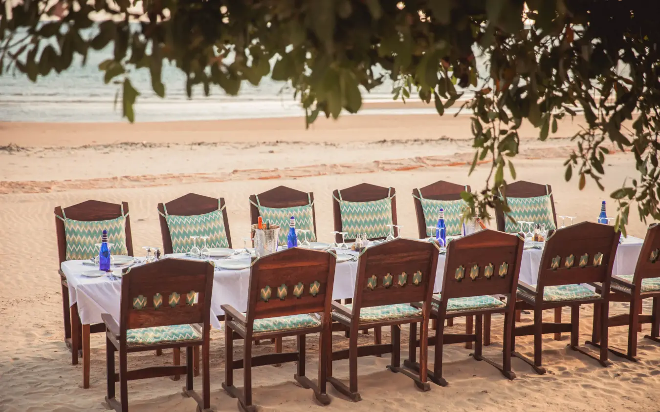 Beachside dining setup with wooden chairs and white tablecloth, The Fort, Lamu Archipelago, Kenya